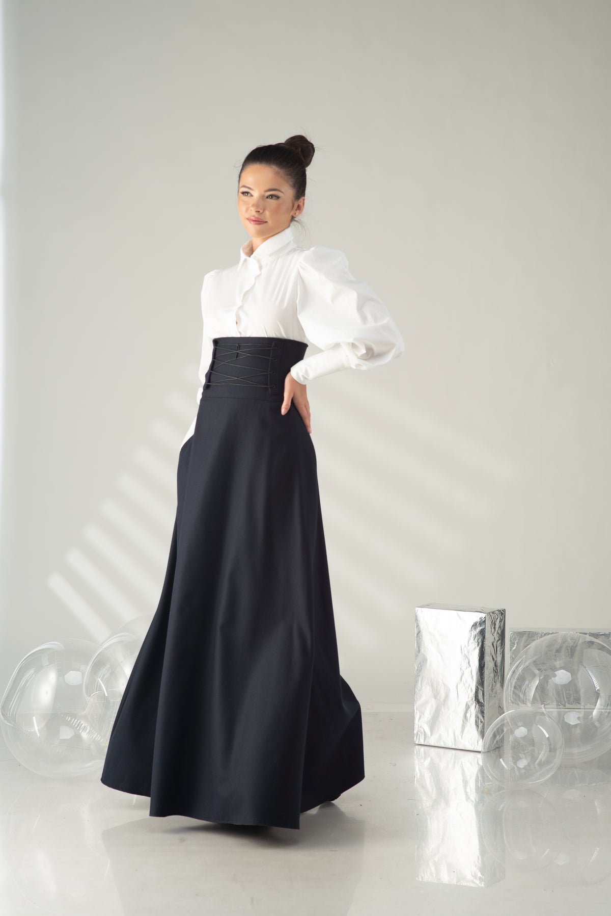 Woman wearing a white blouse and black skirt against a plain background