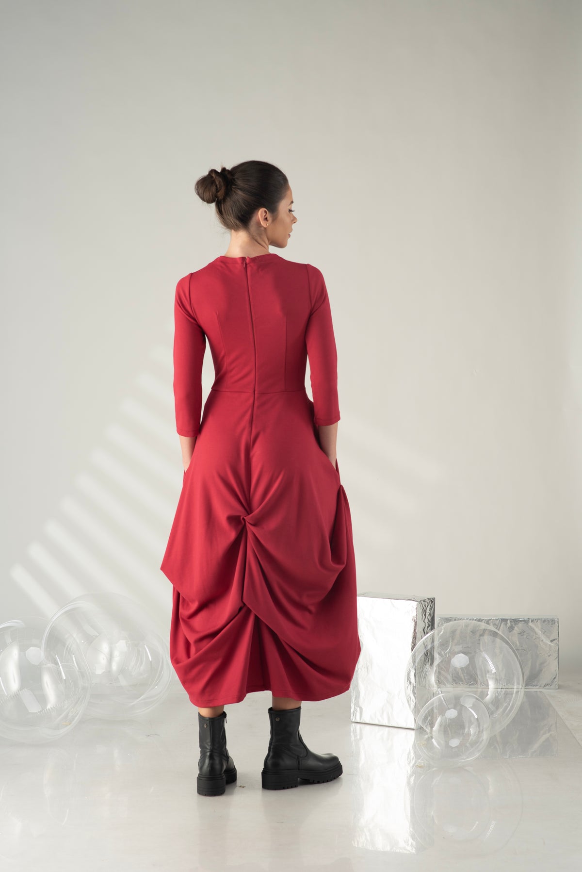 Woman wearing a red dress with a unique design, standing against a white background.