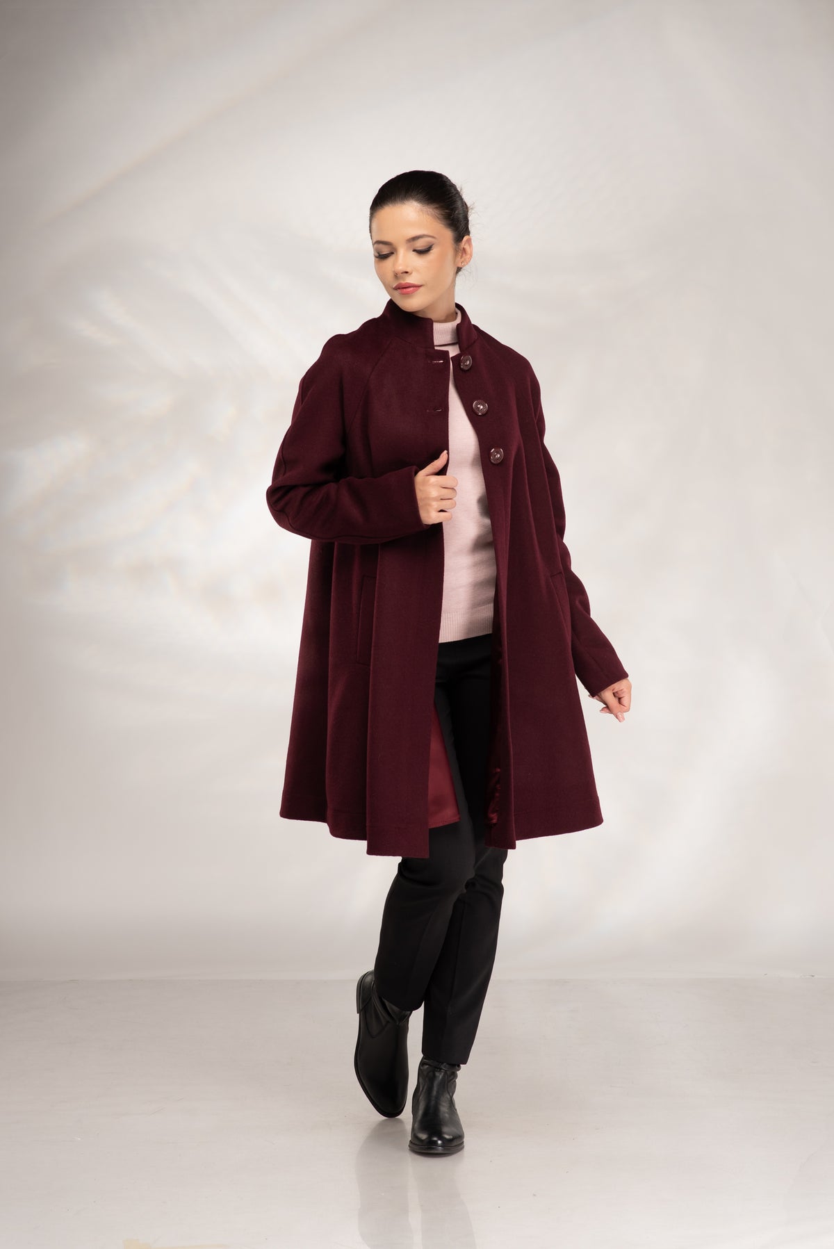 Women's burgundy wool coat styled open showing the inner lining and button front.
