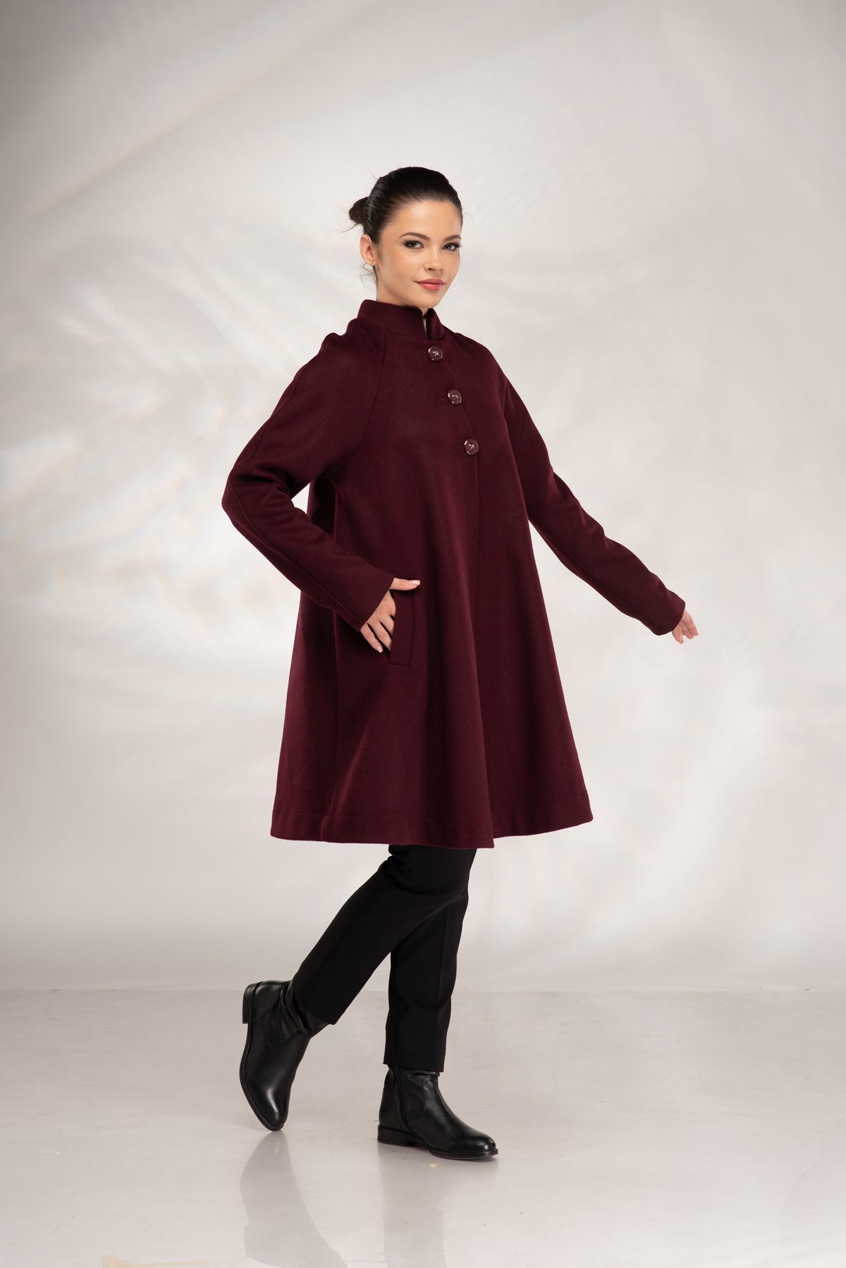 Women's burgundy wool coat with discreet side pockets and elegant flared silhouette.