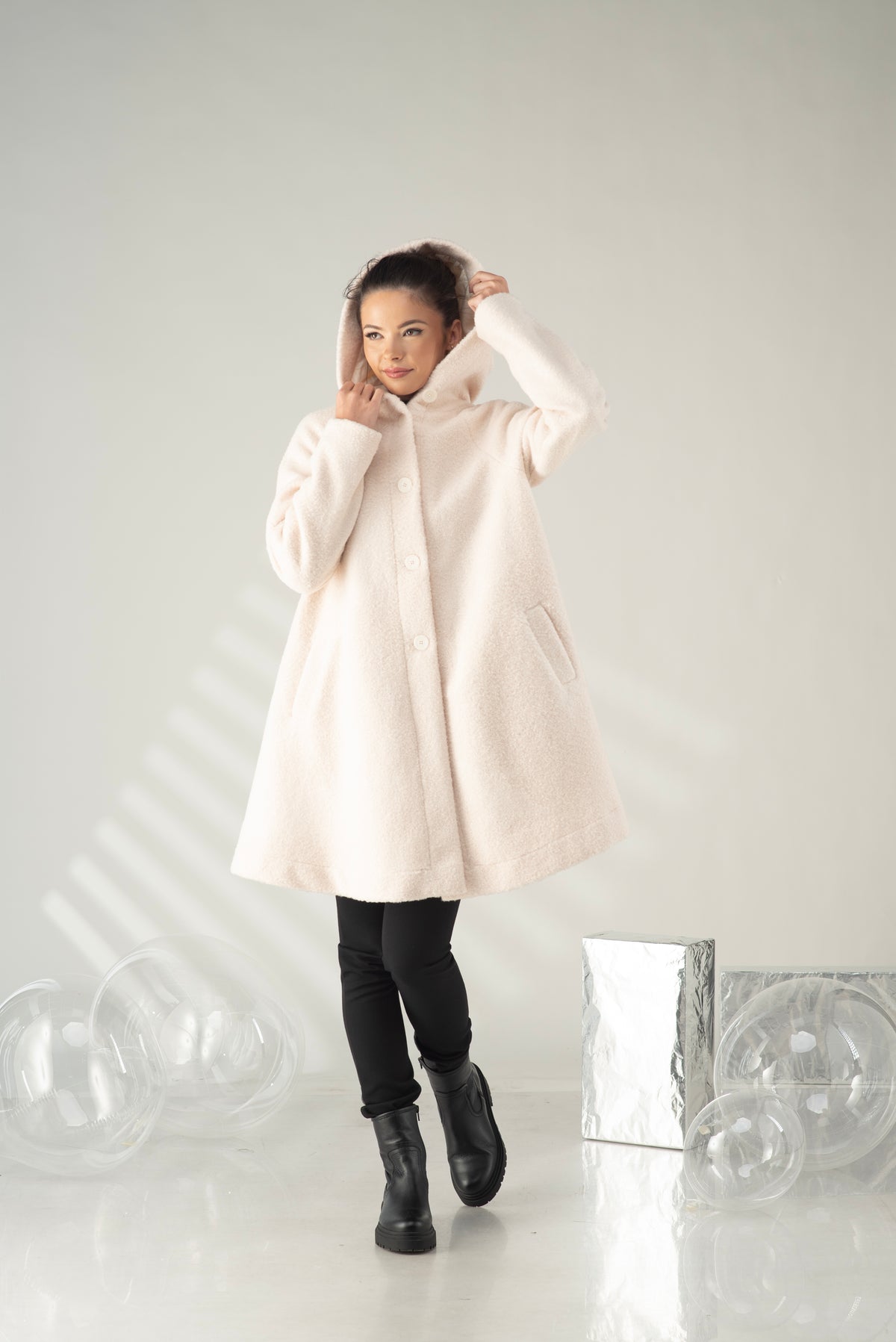 Women's hooded A-line swing coat styled with black leggings and boots