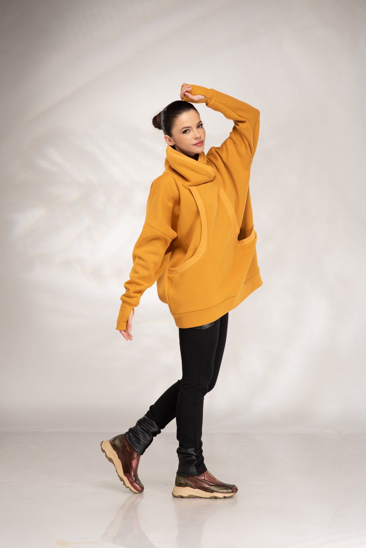 Mustard cowl neck hoodie styled with black leggings and casual sneakers