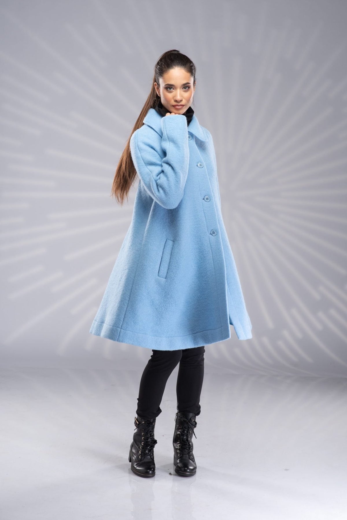 A woman wearing a blue swing coat with buttons, two pockets, and an A-line silhouette.